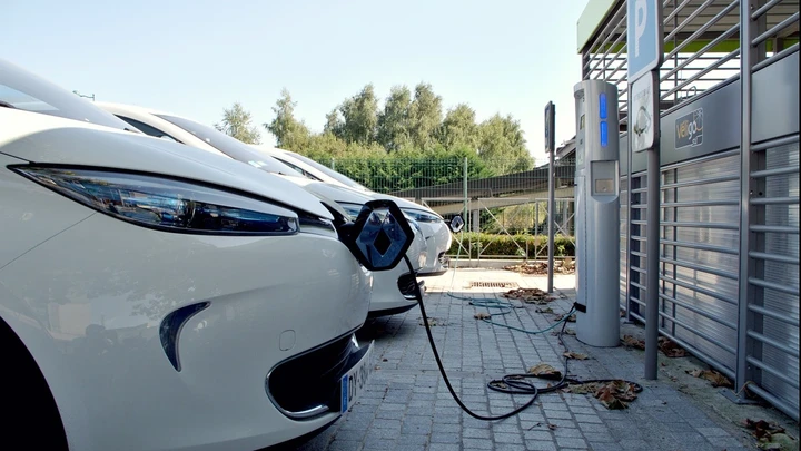 Weiße Elektroautos an Ladesäulen auf einem Parkplatz